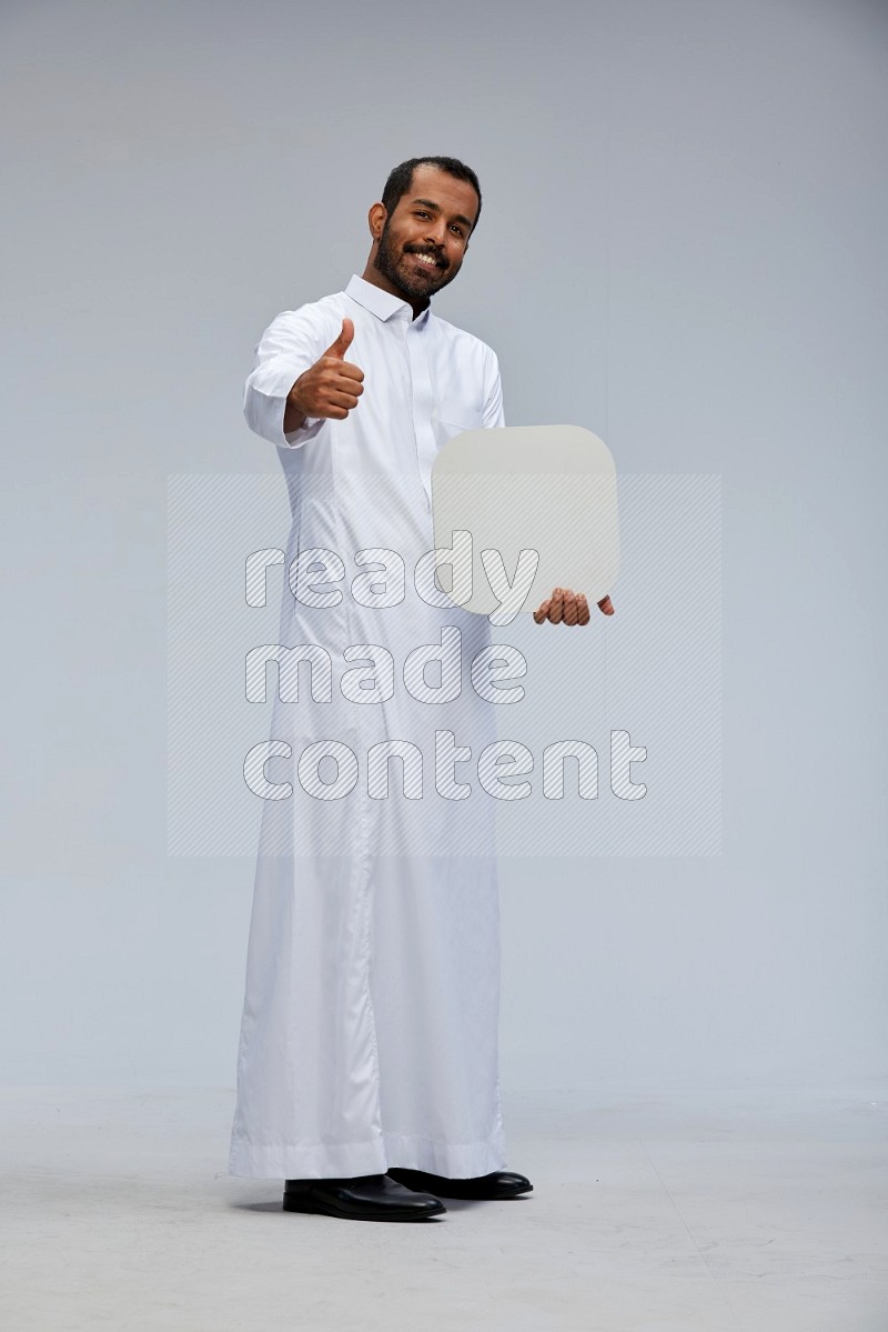 Saudi man wearing Thob standing holding social media sign on Gray background