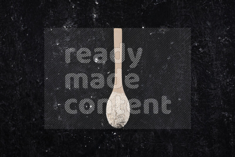 A wooden spoon full of onion powder on black background