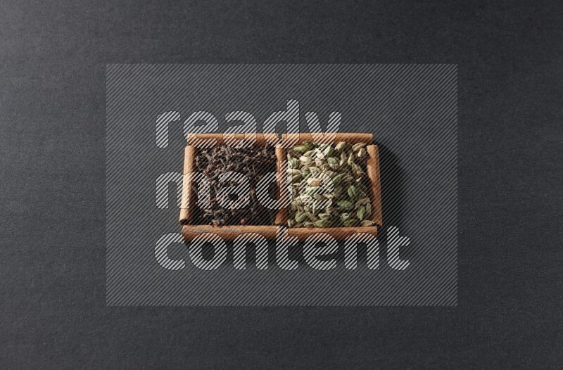 2 squares of cinnamon sticks full of cardamom and cloves on black flooring