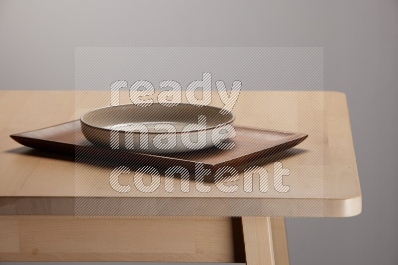 multicolored plate on a rectangular wooden tray on the edge of wooden table
