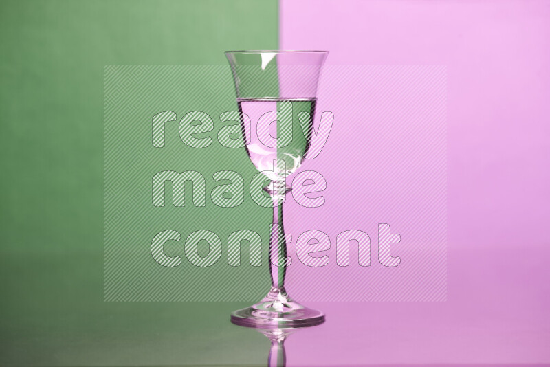 The image features a clear glassware filled with water, set against green and light purple background