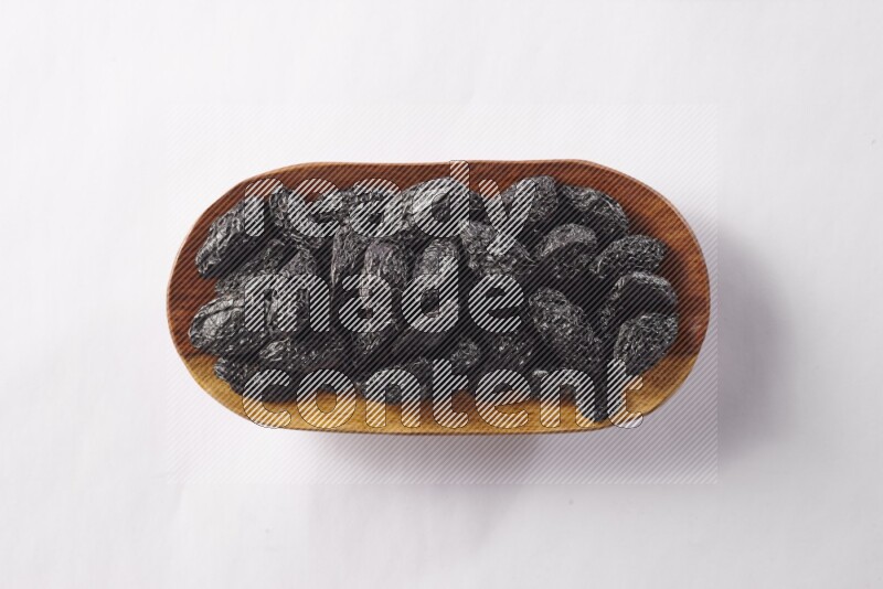 قراصيا في صحن خشبي على خلفية بيضاء