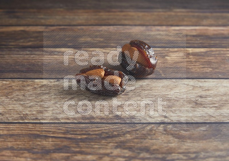 two almond stuffed madjoul dates on a wooden background