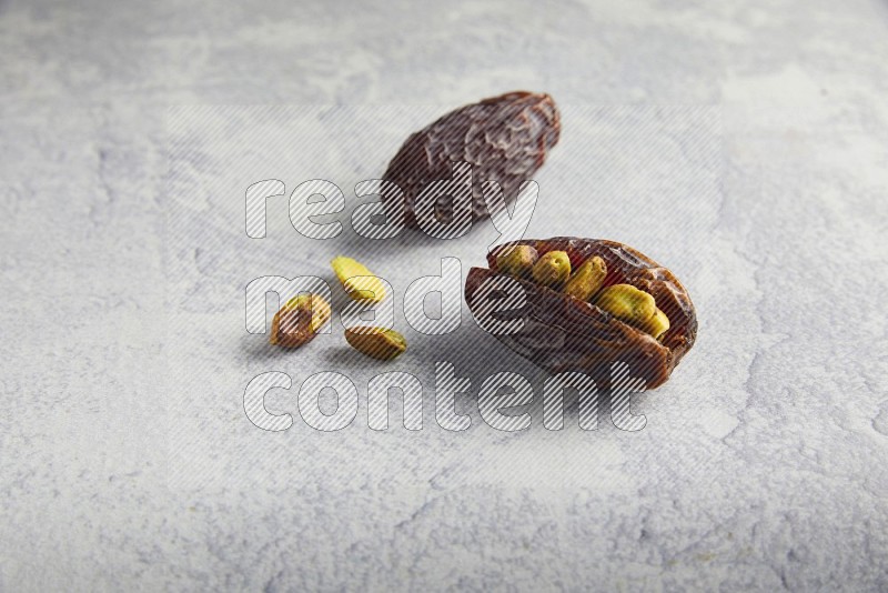 two pistachio stuffed madjoul date on a light grey background