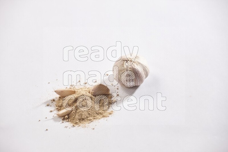A small pile of garlic powder with some of cloves and a whole garlic bulb on a white flooring