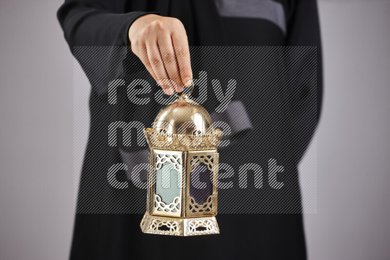 A woman in black abaya holding different ramadan lanterns in different positions