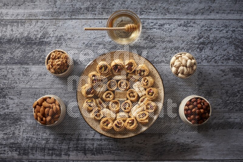 Oriental sweets in a pottery plate with nuts, coffee and honey in a dark setup