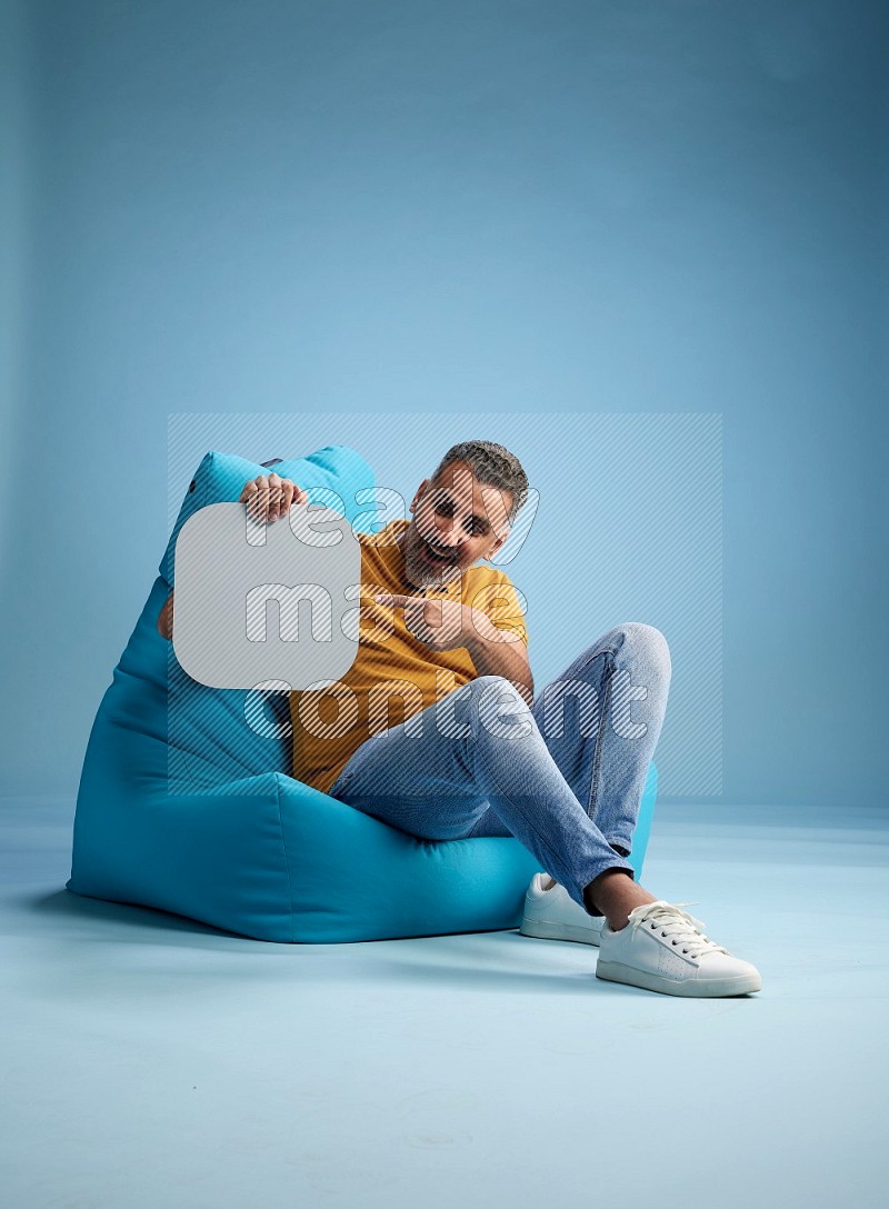 A man sitting on a blue beanbag and holding social media sign