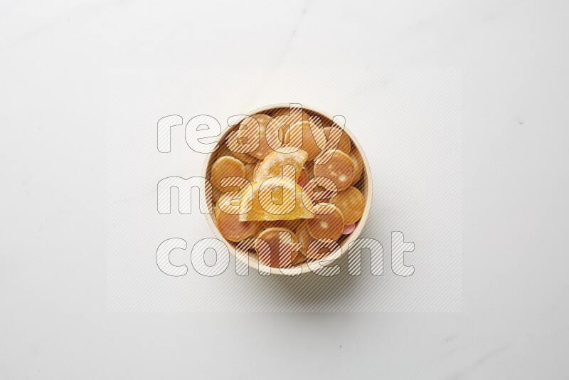 Top-view shot of orange candy cereal pancakes in a round bowl on white background