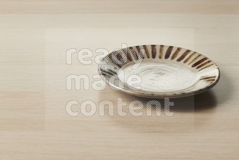 A multicolored pottery plate on light wooden background