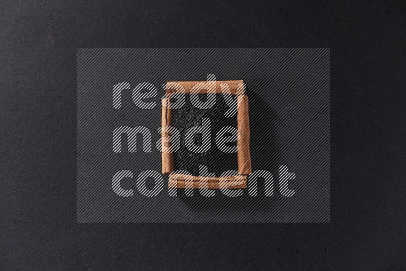 A single square of cinnamon sticks full of black seeds on black flooring