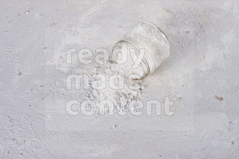 A glass jar full of coarse sea salt crystals on white background