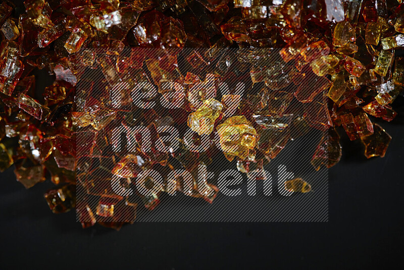 Transparent orange fragments of glass scattered on a black background