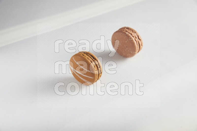 45º Shot of of two assorted Brown Irish Cream, and Brown Hazelnuts macarons on white background