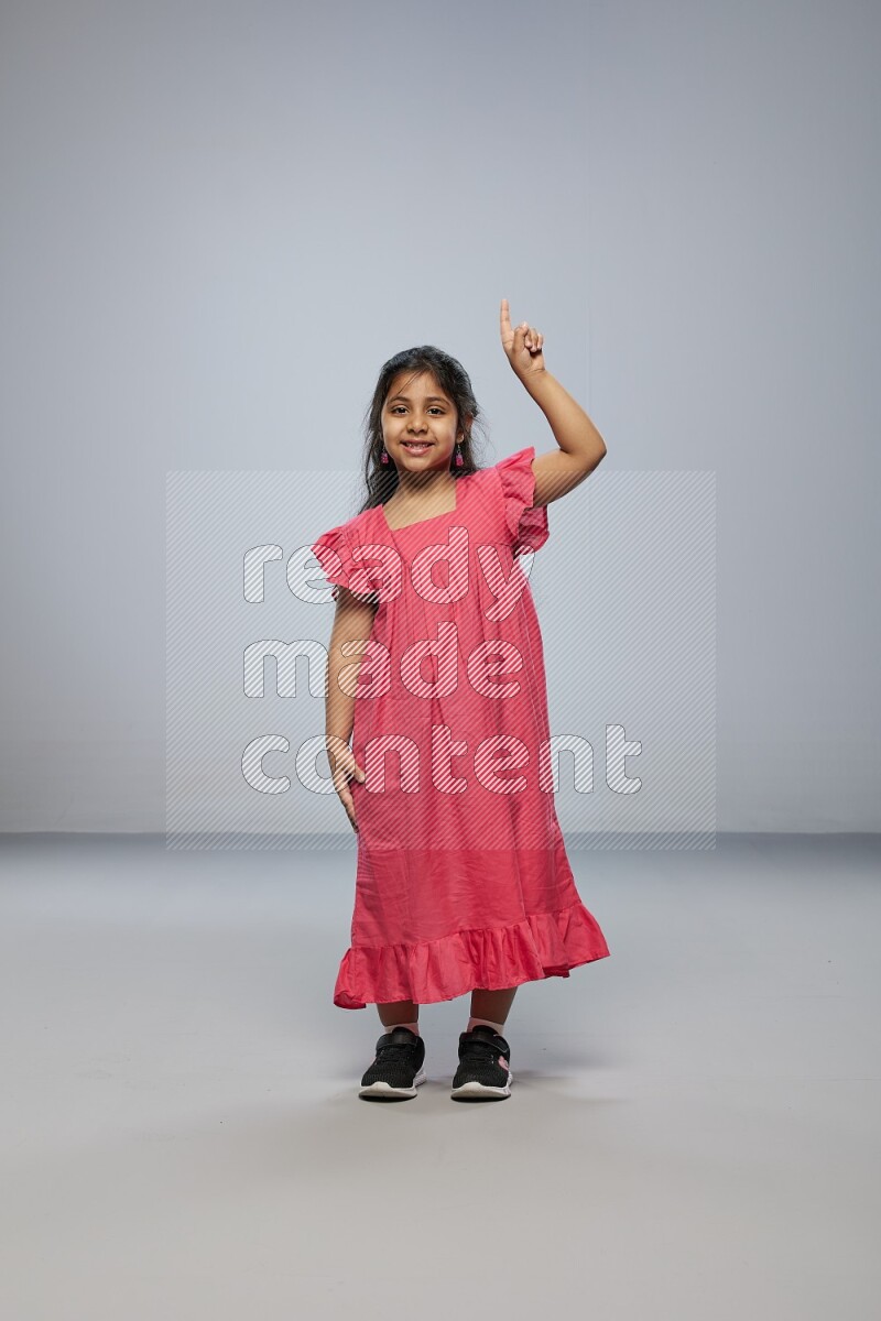 A girl standing interacting with the camera on gray background