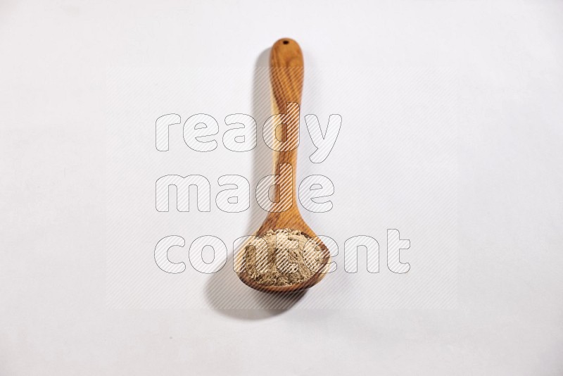 A wooden ladle full of garlic powder on a white flooring