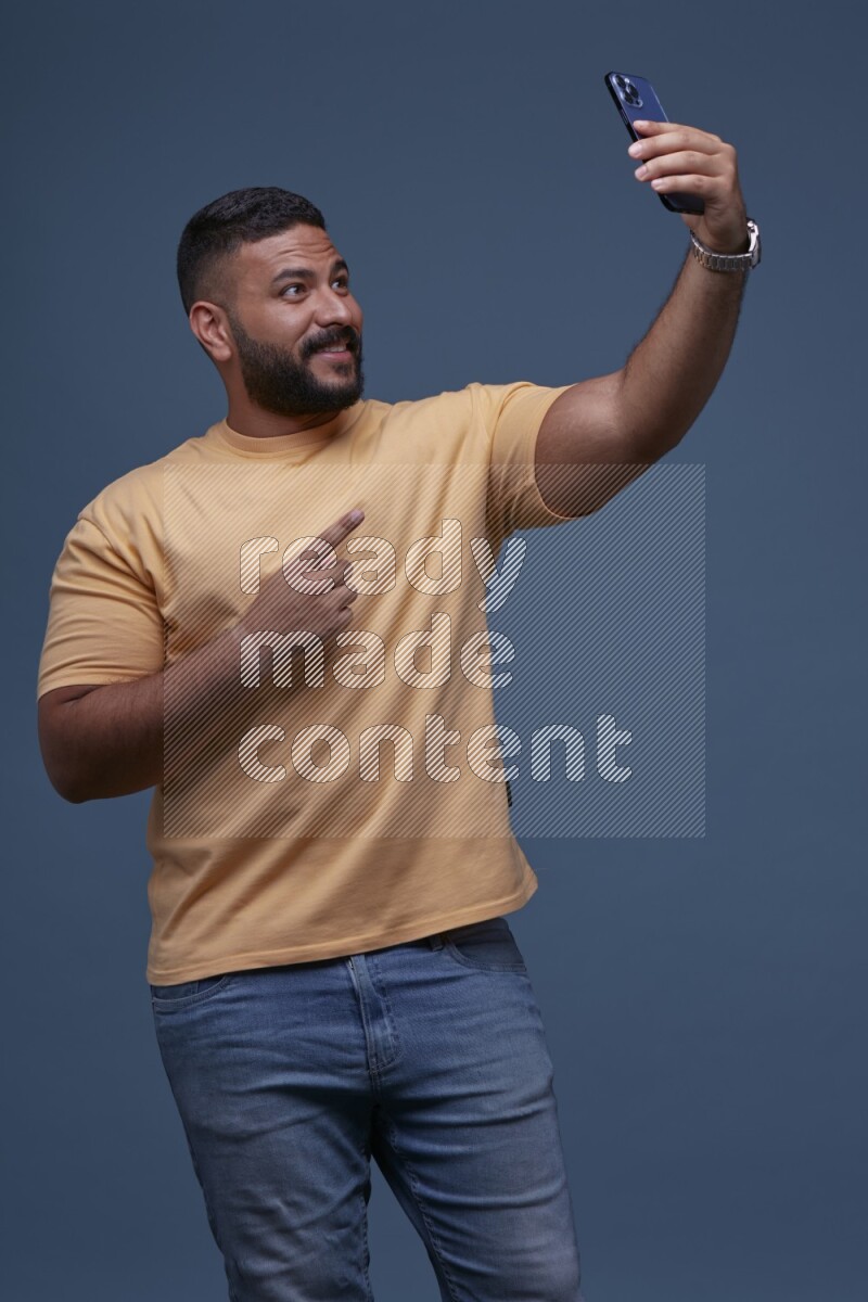 A man Taking A Selfie on Blue Background wearing Orange T-shirt