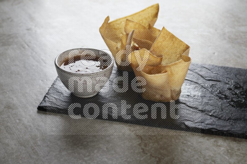 wonton cups with soy sauce ramkin on rectangle slate on grey textured counter top