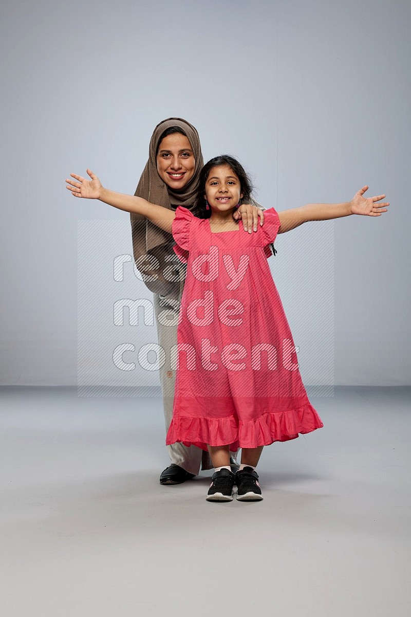 A girl and her mother interacting with the camera on gray background