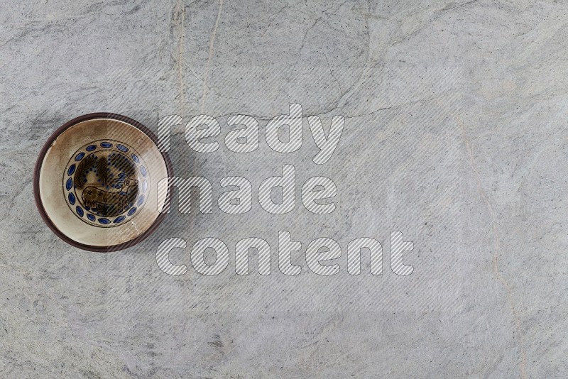 Top View Shot Of A Decorative Pottery Plate On Grey Marble Flooring