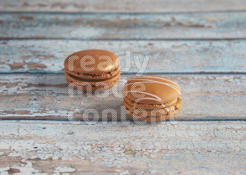 45º Shot of of two assorted Brown Irish Cream, and Brown Coffee macarons on light blue background