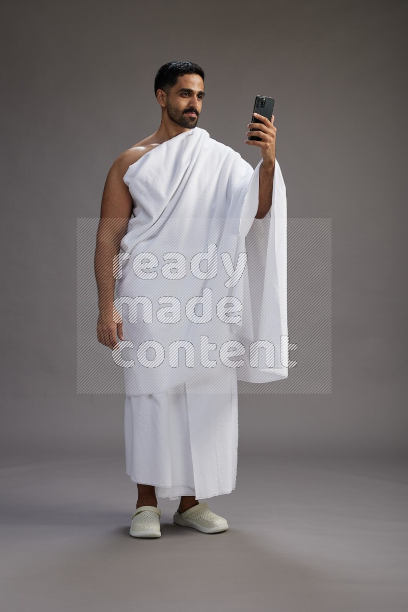 A man wearing Ehram Standing taking selfie on gray background