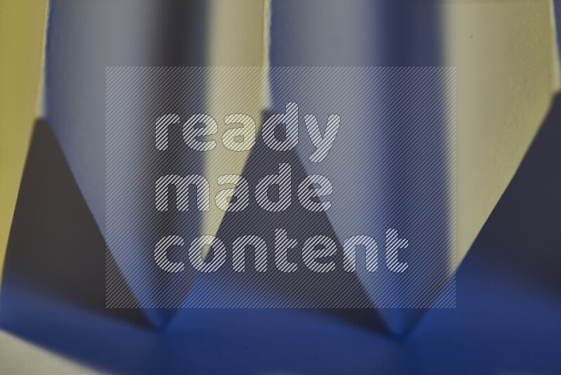 صورة مجردة مقربة تظهر طيات ورقية هندسية حادة بتدرجات اللون الأزرق مع درجات لونية دافئة