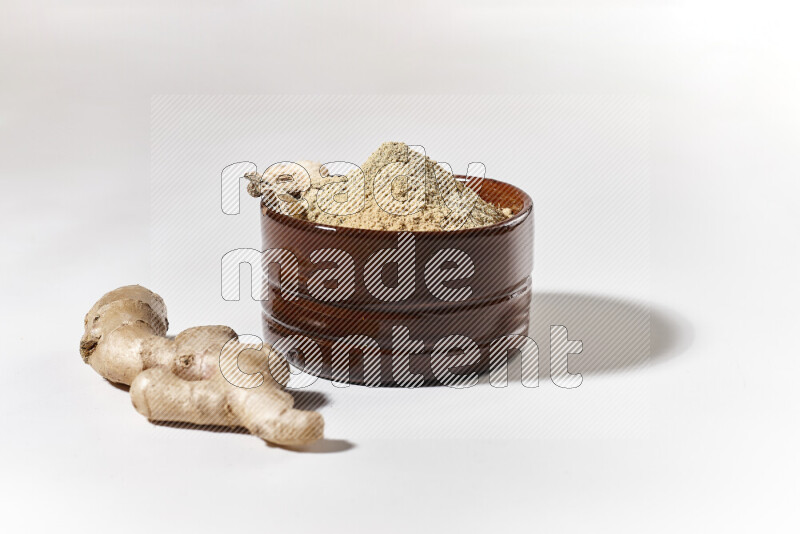 A brown pottery bowl full of ground ginger powder on white background