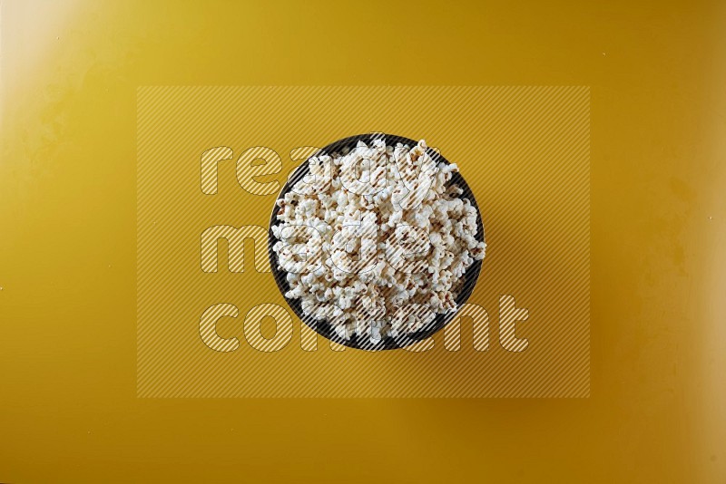 A copper ceramic bowl full of popcorn on a yellow background in different angles