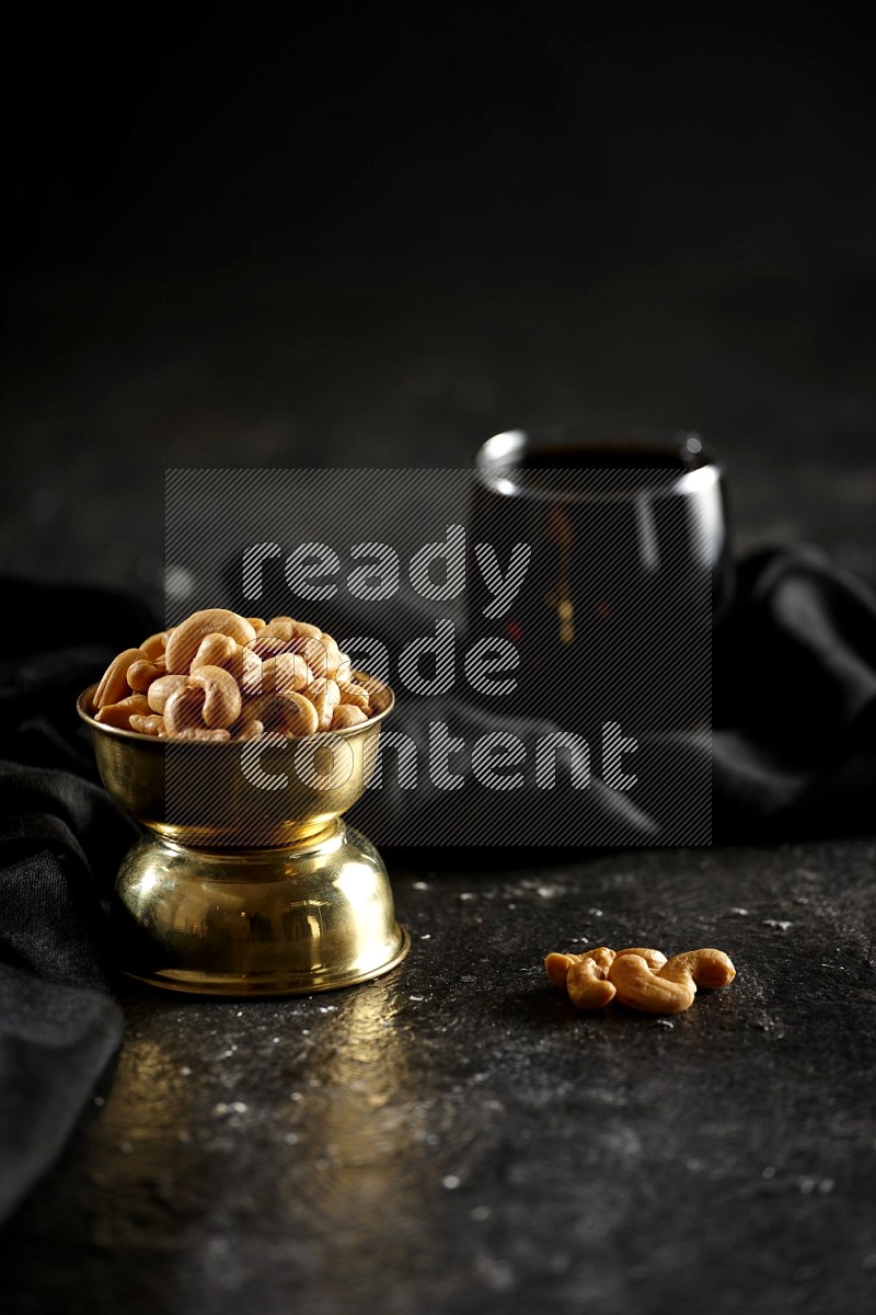 Nuts in a metal bowl with tamarind and a napkin in a dark setup