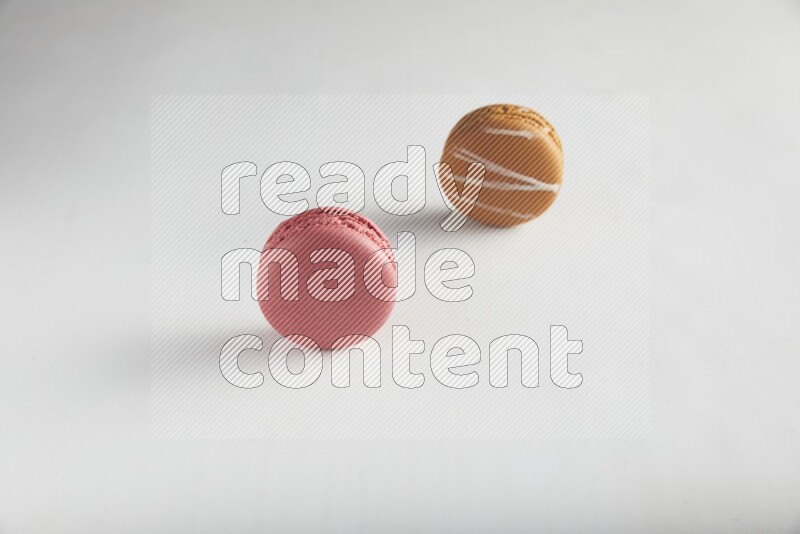 45º Shot of of two assorted Brown Irish Cream, and Pink Raspberry macarons on white background