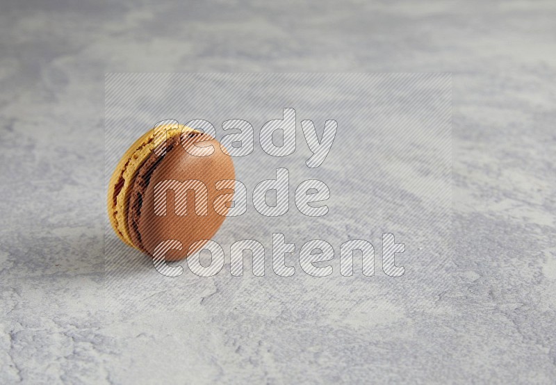 45º Shot of Yellow and Brown Chai Latte macaron on white  marble background