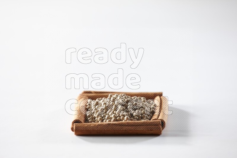 A single square of cinnamon sticks full of white pepper on white flooring
