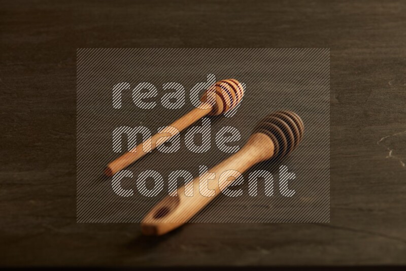 Wooden honey dipper on black slate background