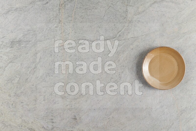 طبق دائري من الفخار باللون البيج على خلفية من الرخام الرمادي