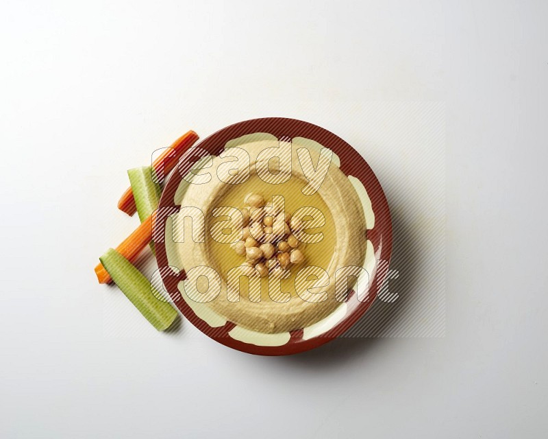 Hummus in a traditional plate garnished with roasted chickpeas  on a white background