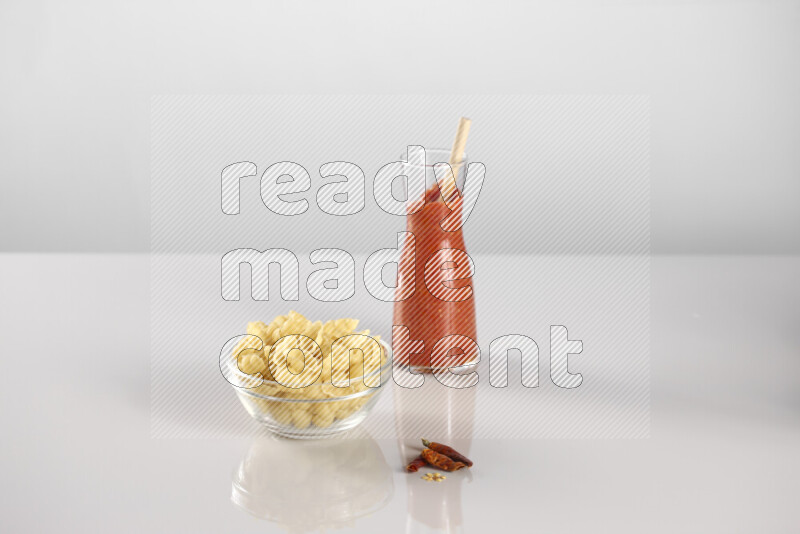 Raw pasta with tomatoe pasta with different ingredients such as cherry tomatoes, basil, garlic, bay laurel, cardamom, white pepper, black pepper, red chilis and wheat stalks on light grey background