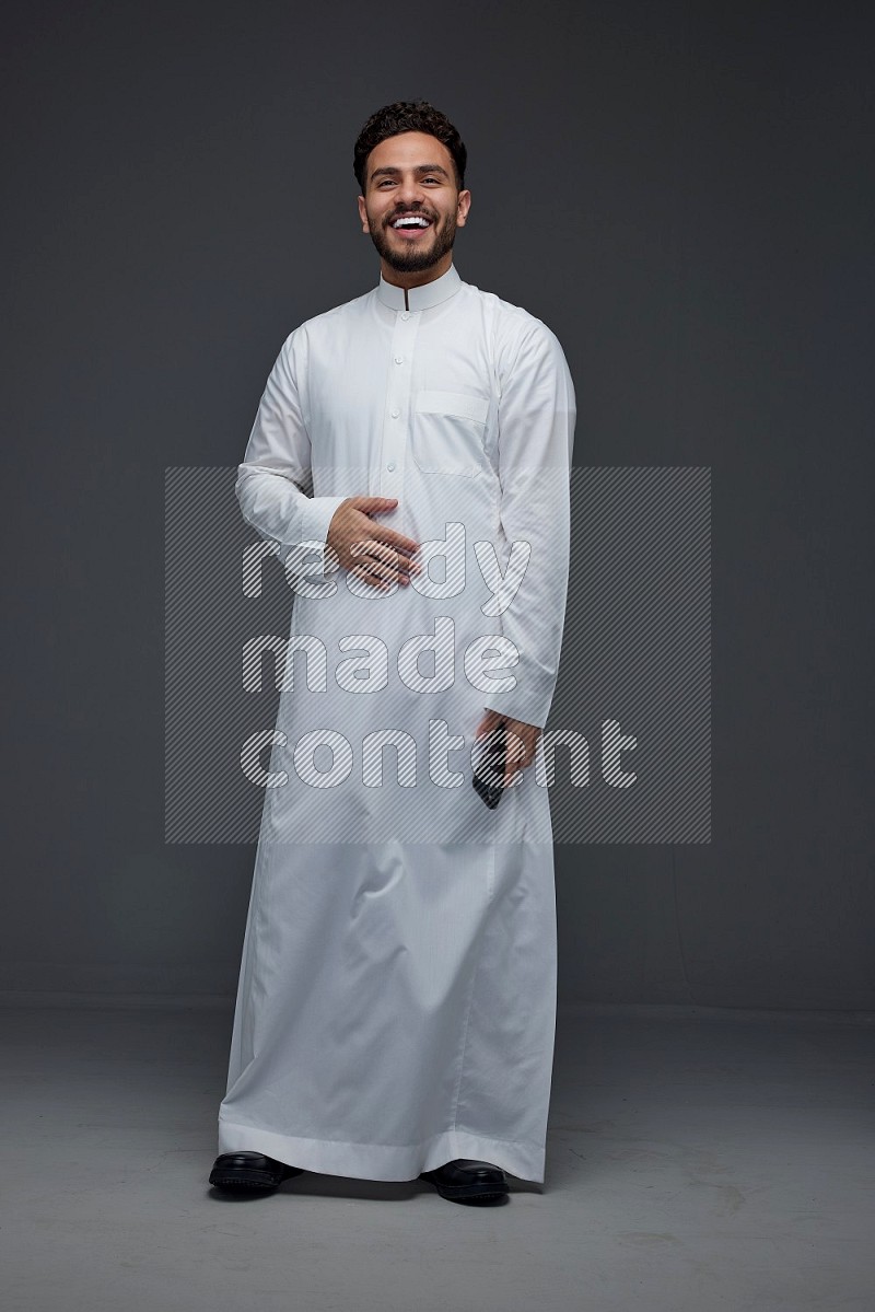 A Saudi man wearing Thobe standing and making different poses eye level on a gray background