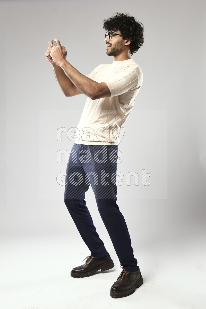 A man wearing casual standing and gaming on the phone on white background