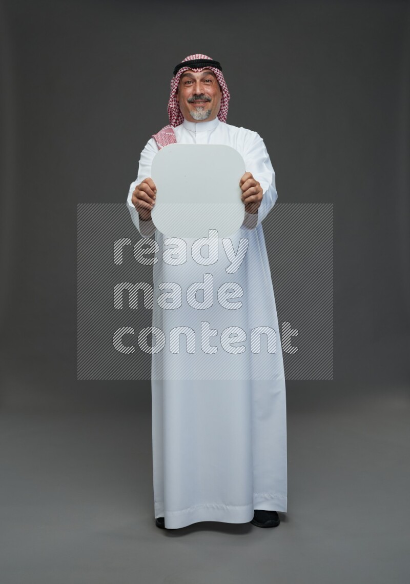 Saudi man with shomag Standing holding social media sing on gray background