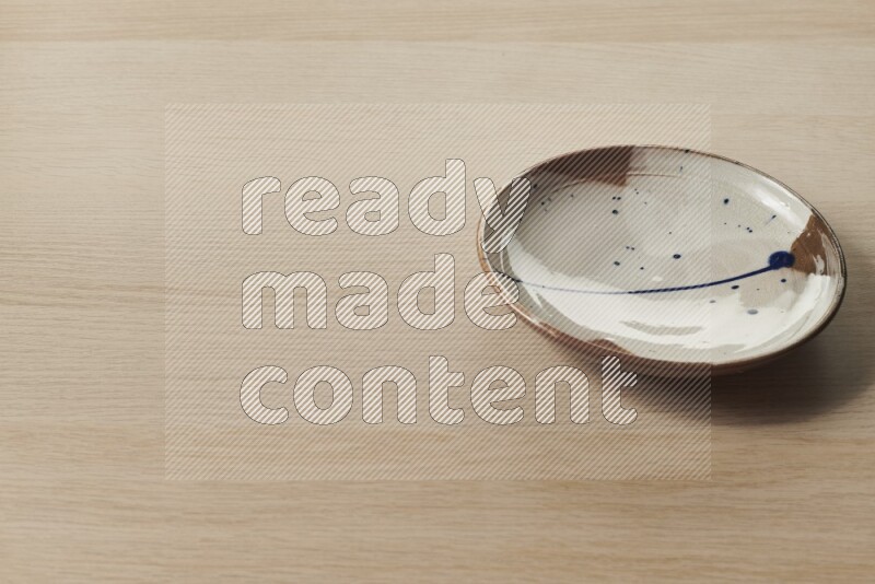 A multicolored pottery plate on light wooden background