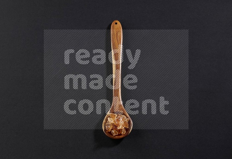A wooden ladle filled with gum arabic on black flooring in different angles