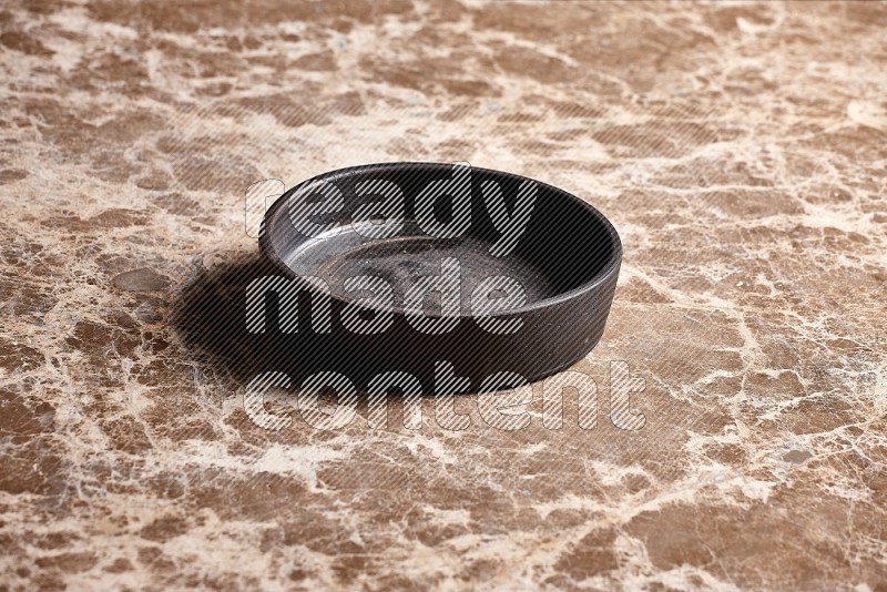 Black Pottery Oven Plate on Beige Marble Flooring, 45 degrees