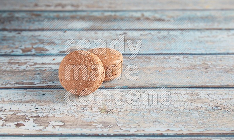 45º Shot of two Brown Hazelnuts macarons on light blue wooden background