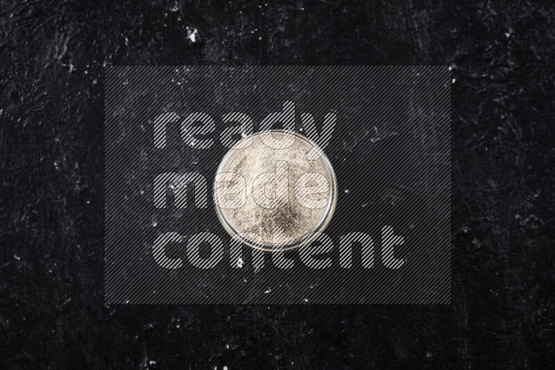 وعاء زجاجي ممتلئ ببودرة البصل علي خلفية سوداء