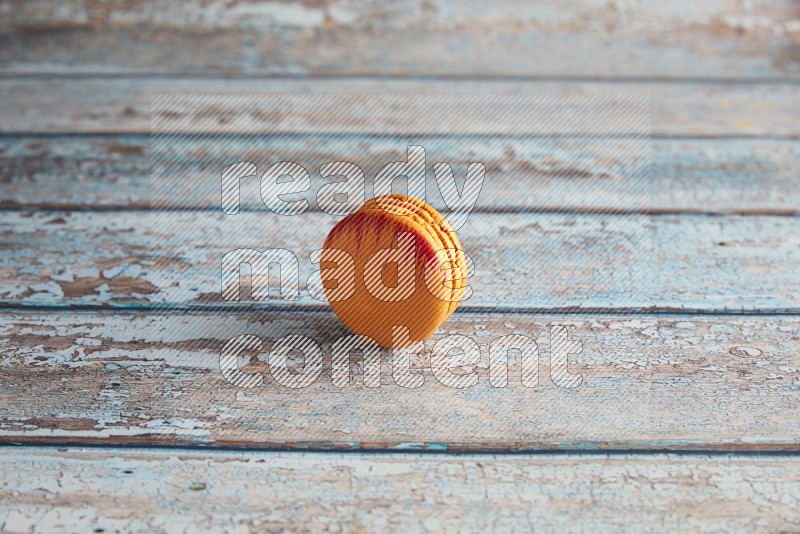 45º Shot of Orange Exotic macaron on light blue wooden background