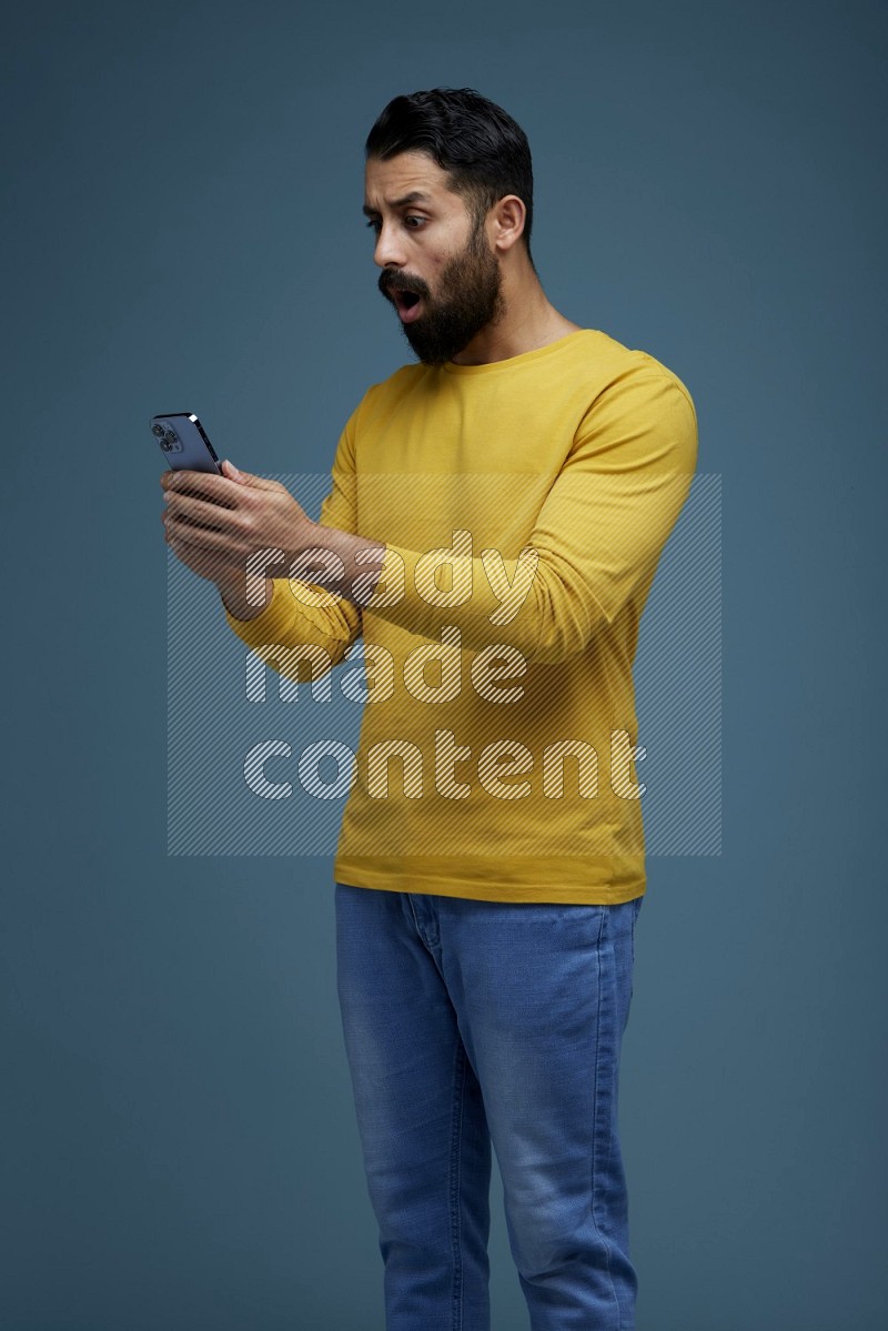 Man typing on his phone in a blue background wearing a yellow shirt