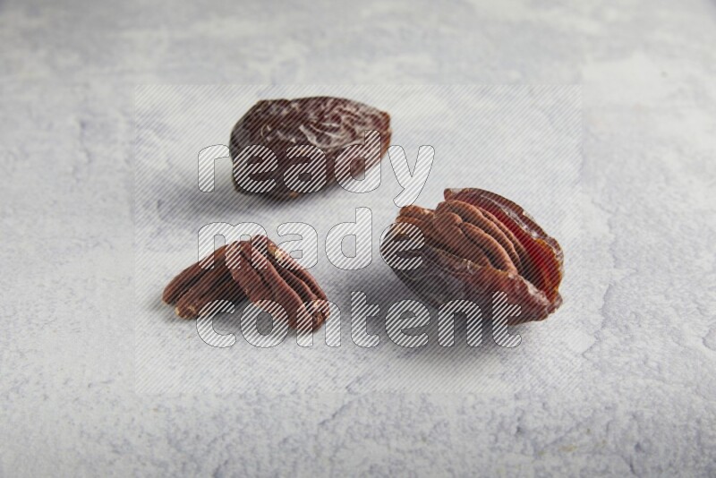 two pecan stuffed madjoul dates on a light grey background