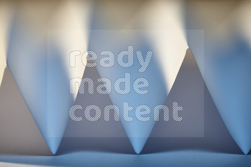 A close-up abstract image showing sharp geometric paper folds in white and blue gradients