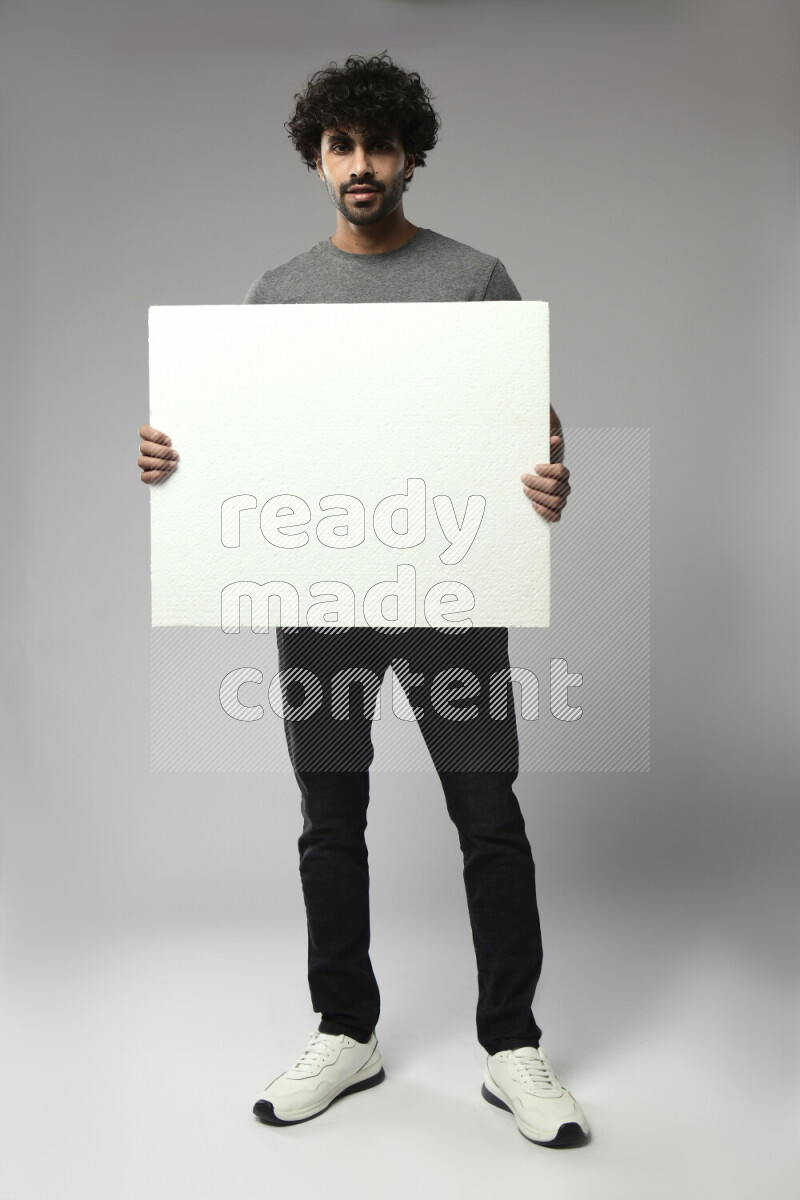 A man wearing casual standing and holding a white board on white background